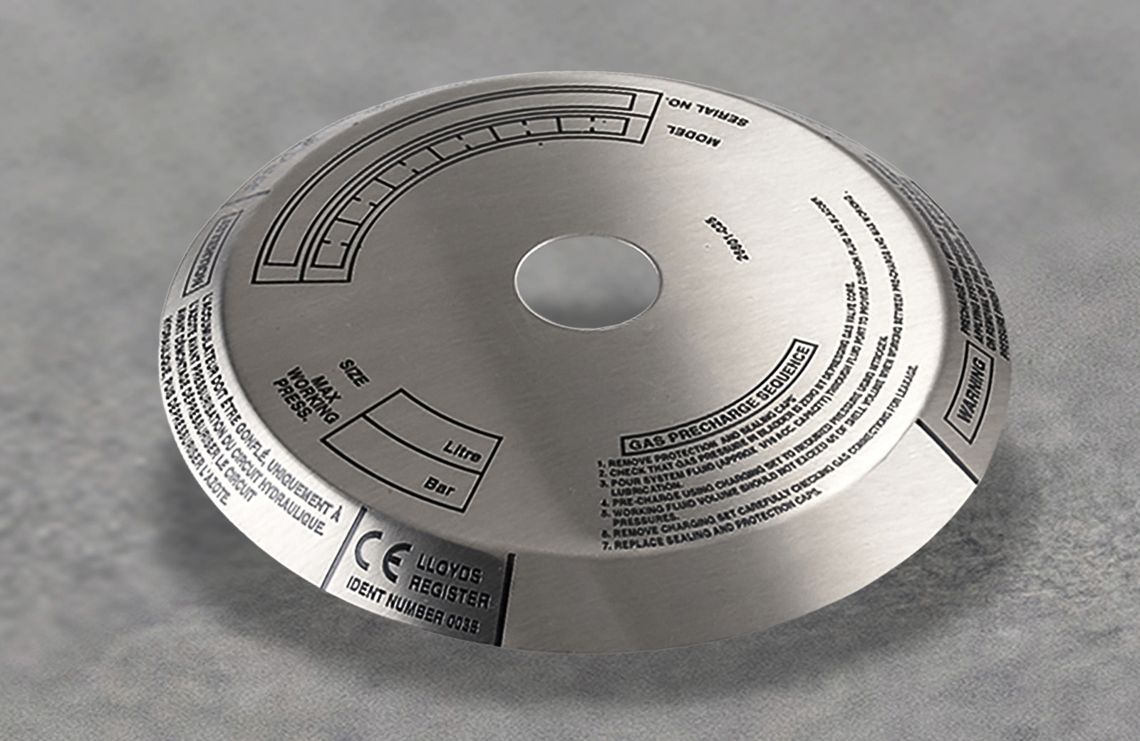 A polished stainless steel badge with printed product information on it.